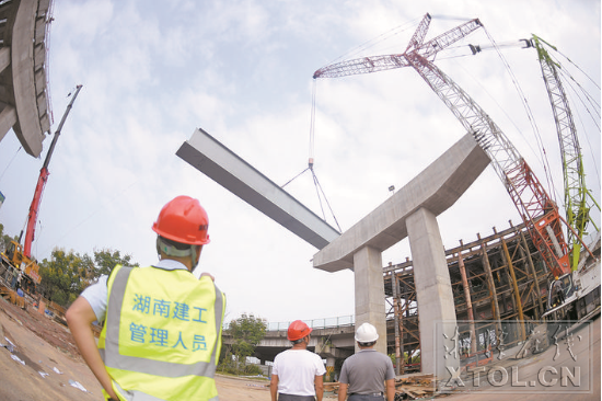 紅易-滬昆跨線橋跨滬昆高速公路主跨架梁施工現(xiàn)場(chǎng)，一節(jié)節(jié)鋼箱梁被吊起安裝。（記者 方陽(yáng) 攝）